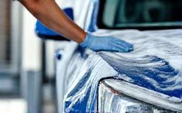 Technician washing car exterior with foam